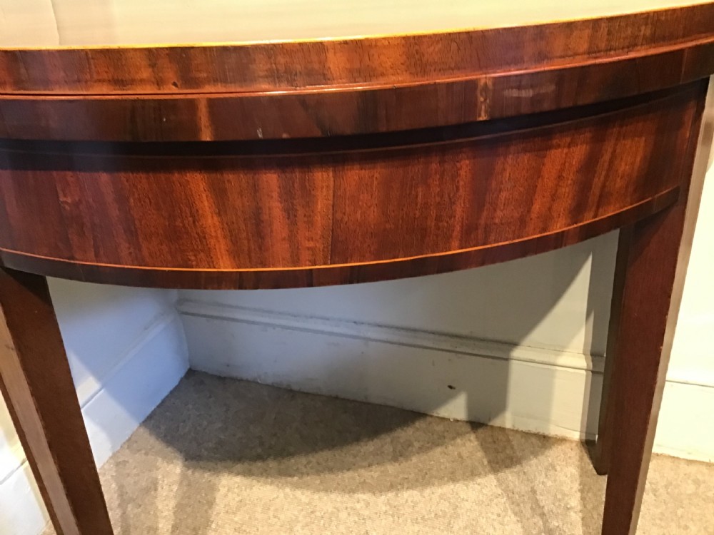 A Georgian dark mahogany demi-lune console table featuring a semicircular top with a central fan inlay motif and square tapered legs. View VI