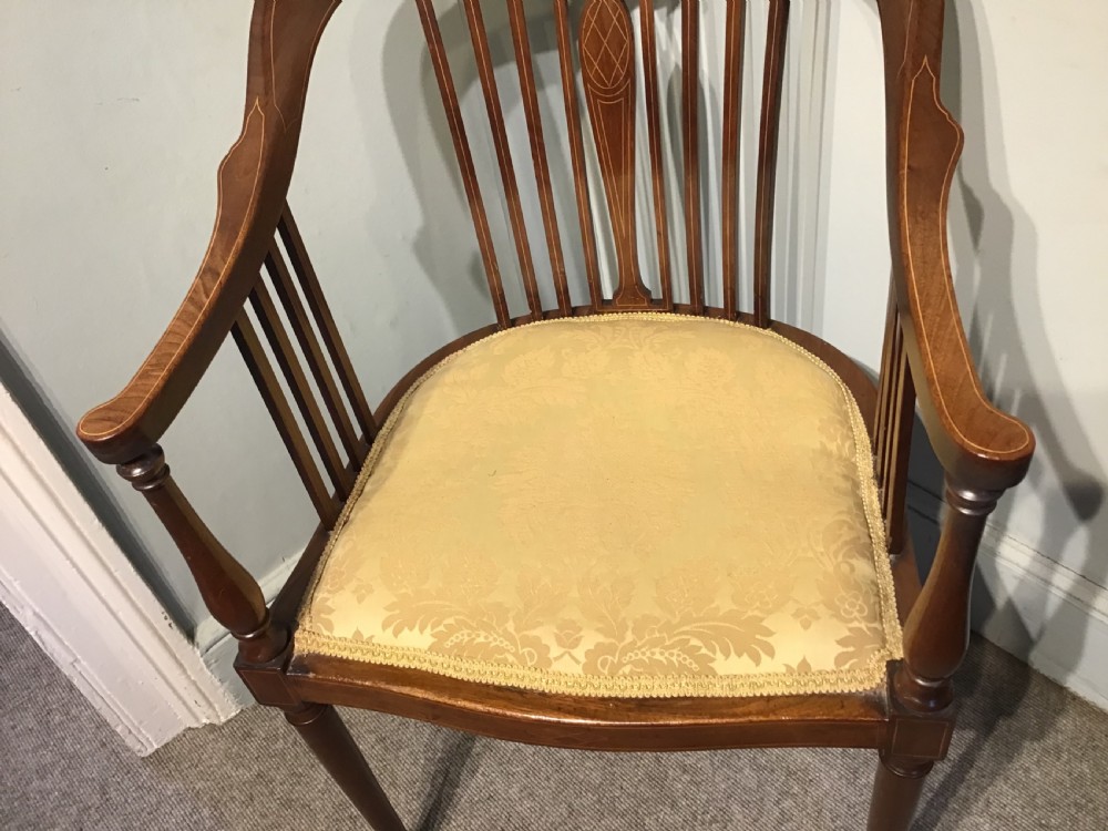 An Edwardian mahogany tub armchair featuring inlaid wood decoration, slender spindles, and a light yellow upholstered seat. View III