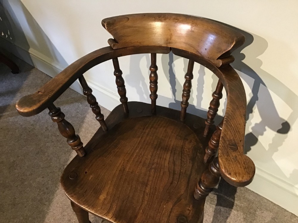 A Victorian smokers bow armchair crafted from polished dark timber, featuring turned spindles, a horseshoe armrest, and a contoured seat. View II