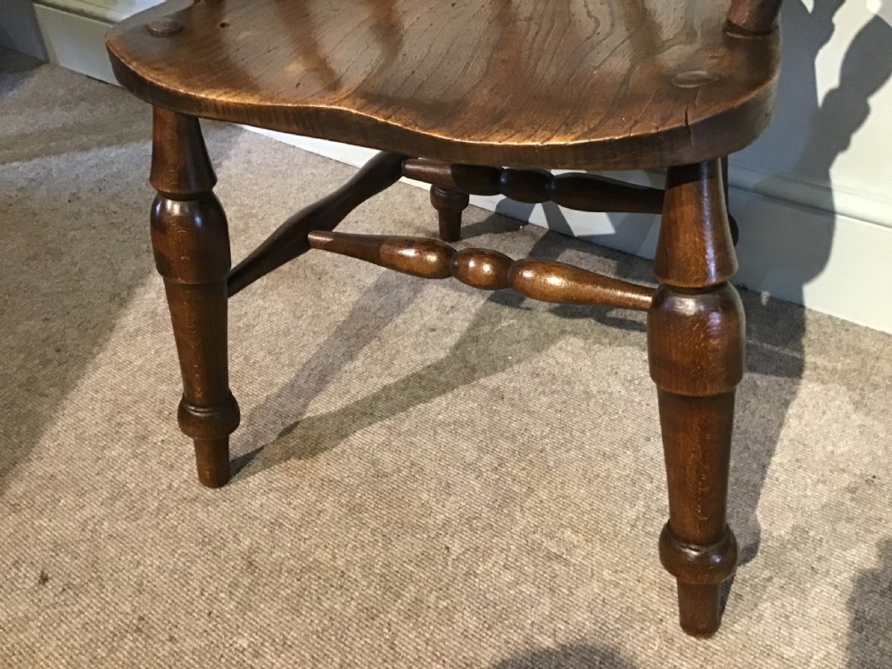 A Victorian smokers bow armchair crafted from polished dark timber, featuring turned spindles, a horseshoe armrest, and a contoured seat. View III
