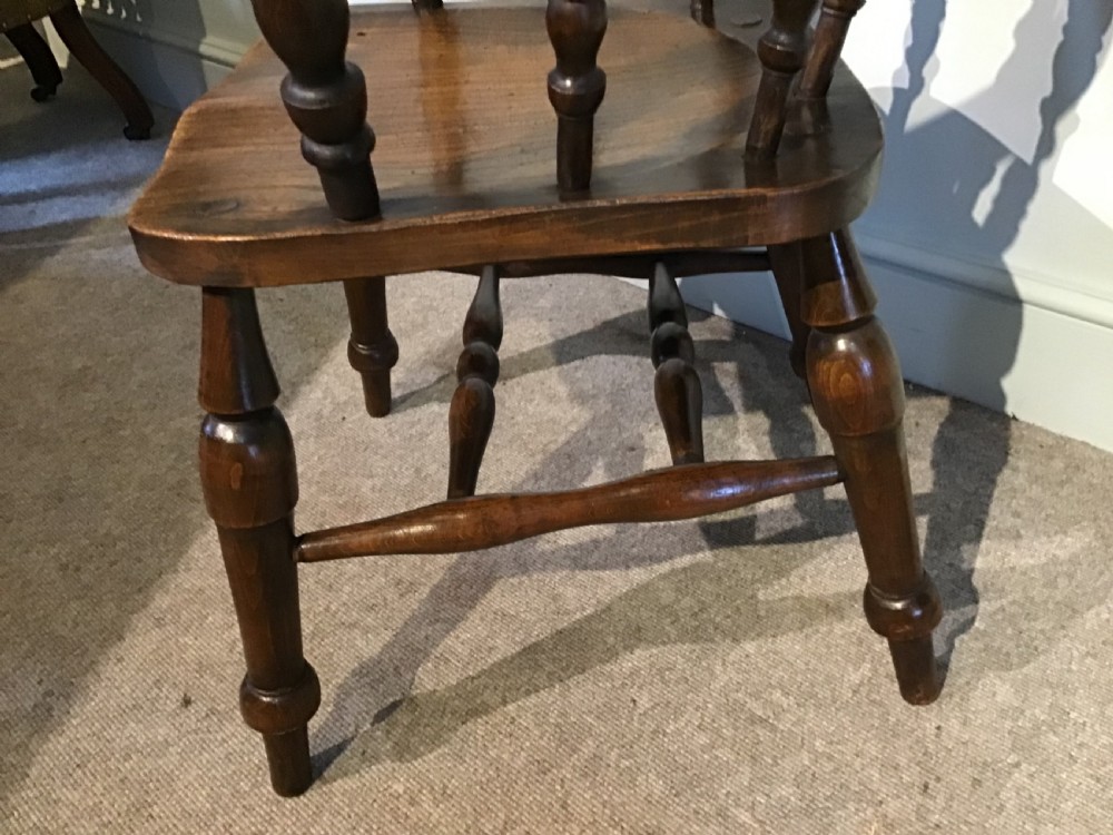 A Victorian smokers bow armchair crafted from polished dark timber, featuring turned spindles, a horseshoe armrest, and a contoured seat. View IV