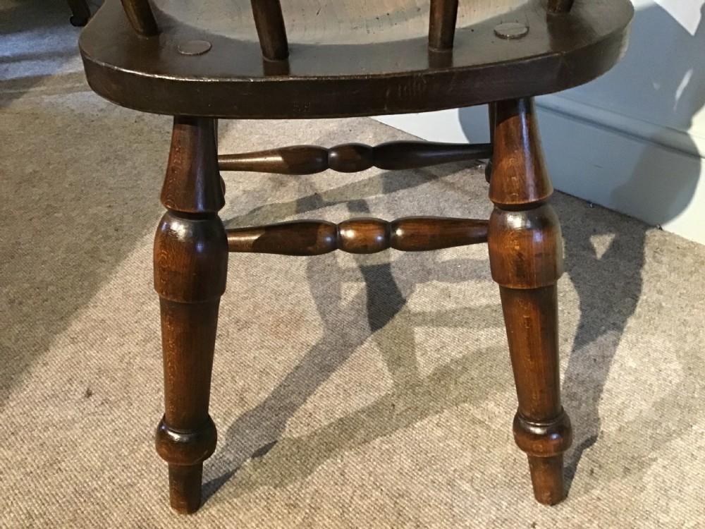 A Victorian smokers bow armchair crafted from polished dark timber, featuring turned spindles, a horseshoe armrest, and a contoured seat. View VI