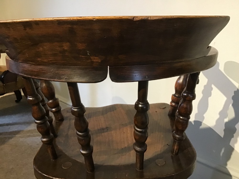 A Victorian smokers bow armchair crafted from polished dark timber, featuring turned spindles, a horseshoe armrest, and a contoured seat. View VII