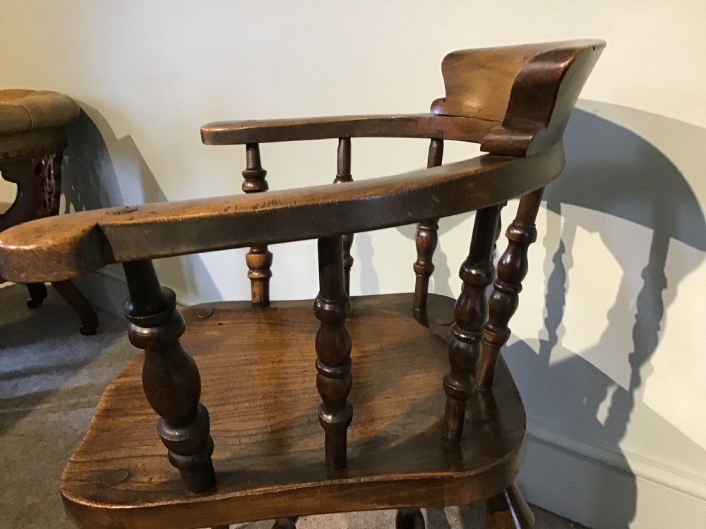 A Victorian smokers bow armchair crafted from polished dark timber, featuring turned spindles, a horseshoe armrest, and a contoured seat. View VIII