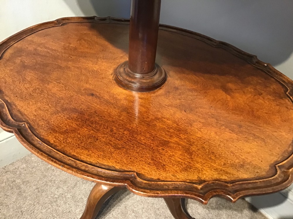 An antique mahogany two-tiered dumb waiter featuring scalloped tray edges, a turned central column, and a tripod base. View III