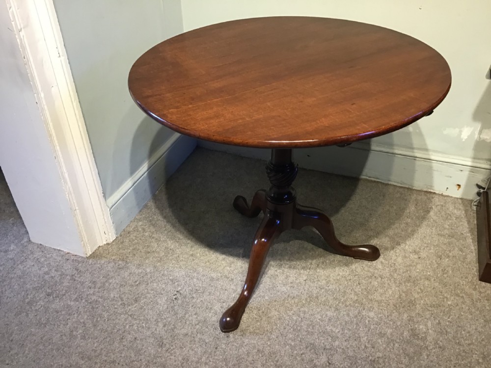 A dark mahogany circular tripod table with a turned central column featuring spiral carving and three cabriole legs with pad feet. View IV