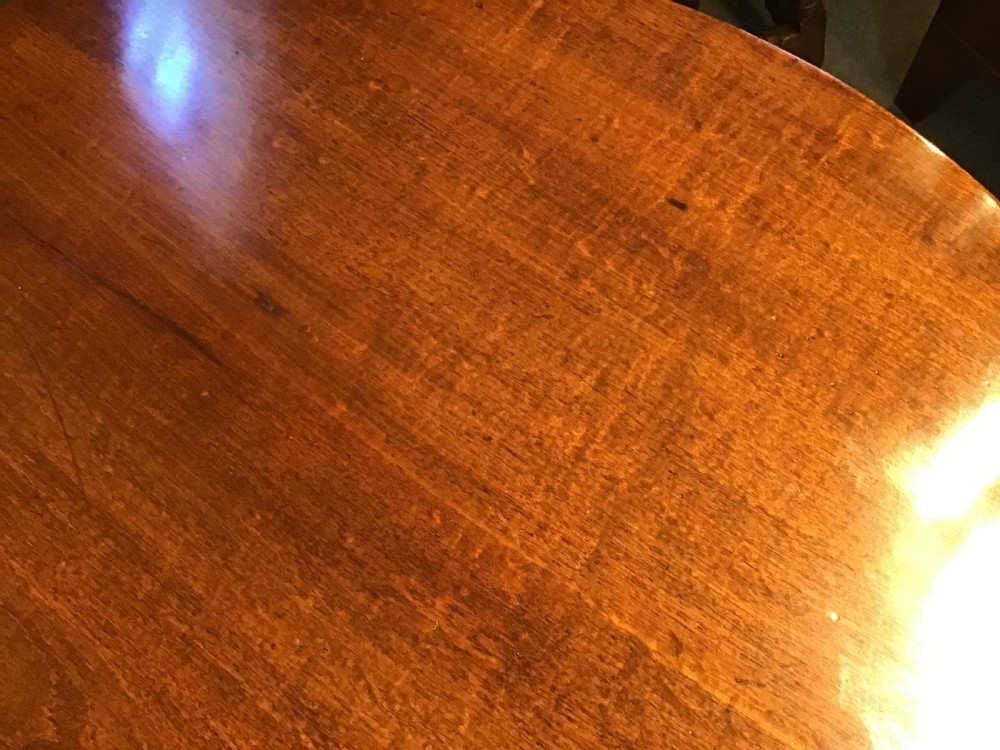 A dark mahogany circular tripod table with a turned central column featuring spiral carving and three cabriole legs with pad feet. View X
