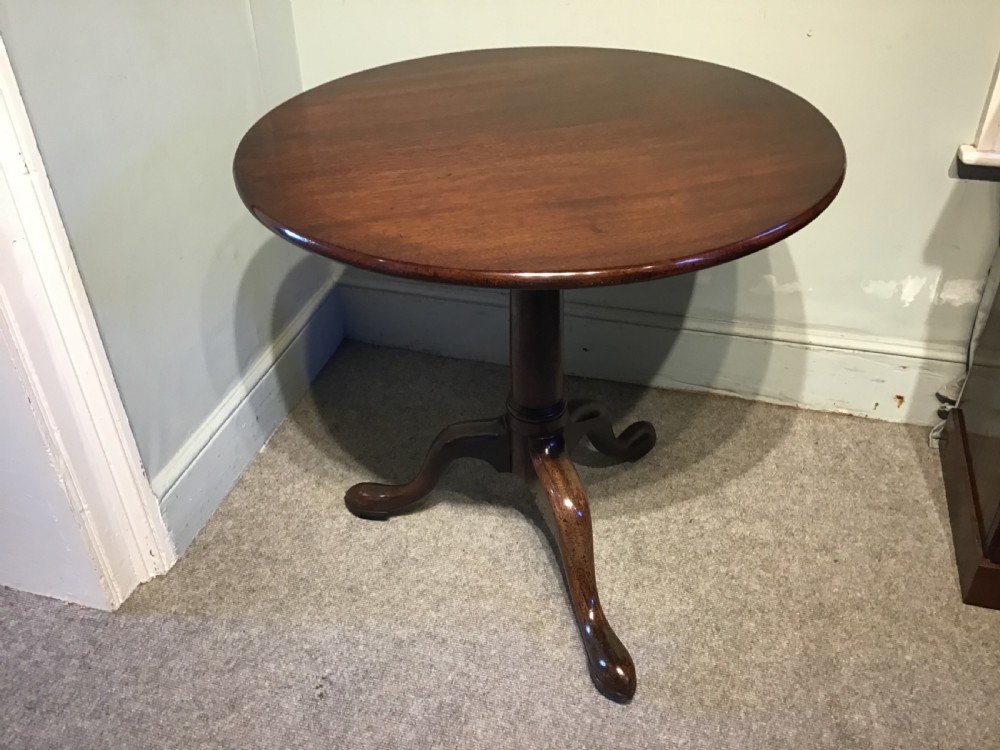 An 18th-century Georgian mahogany tripod table featuring a circular top, a central turned pedestal column, and three splayed cabriole legs.