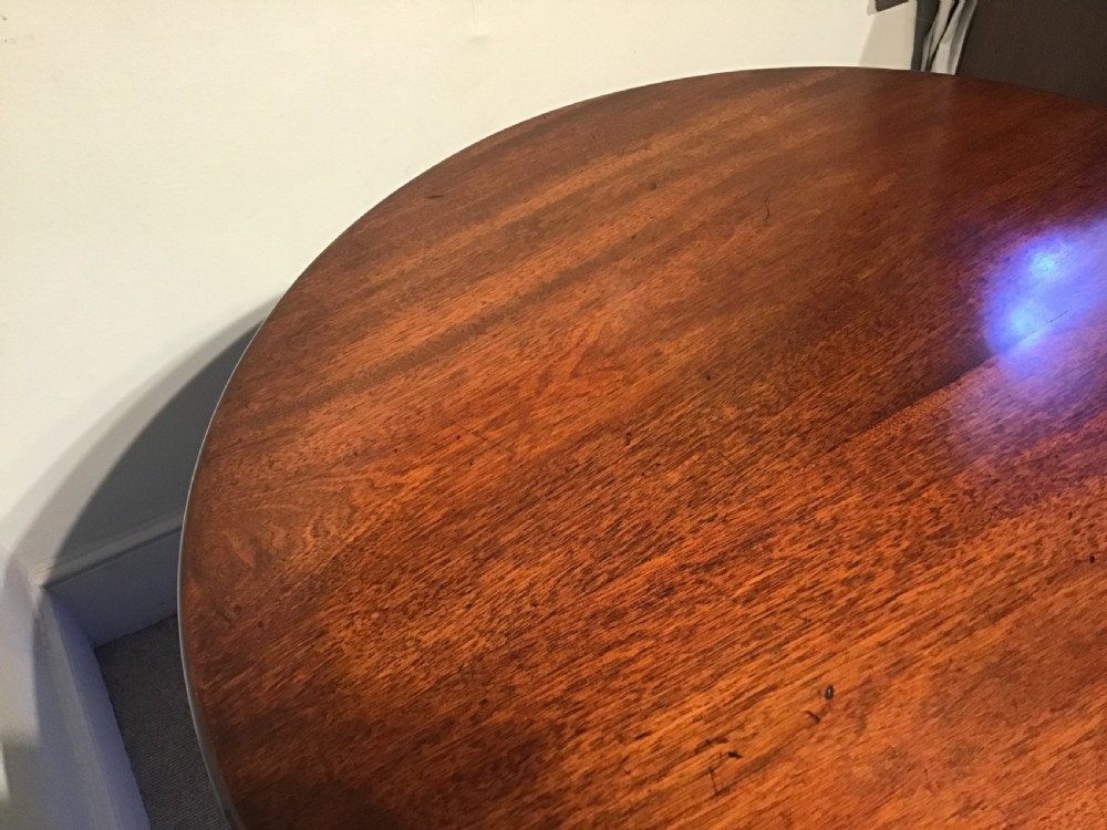 An 18th-century Georgian mahogany tripod table featuring a circular top, a central turned pedestal column, and three splayed cabriole legs. View X