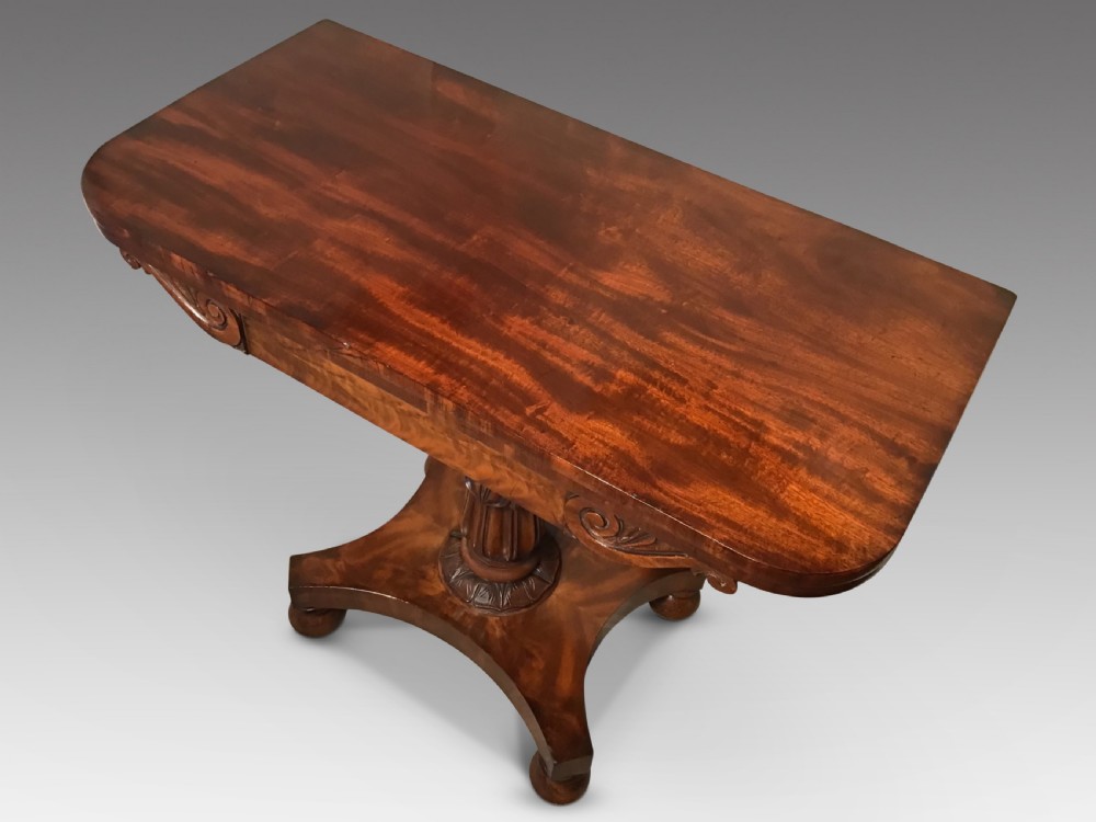 A Regency period flame mahogany fold-over card table featuring a carved pedestal column, a quadruped platform base, and scroll corner brackets. View II