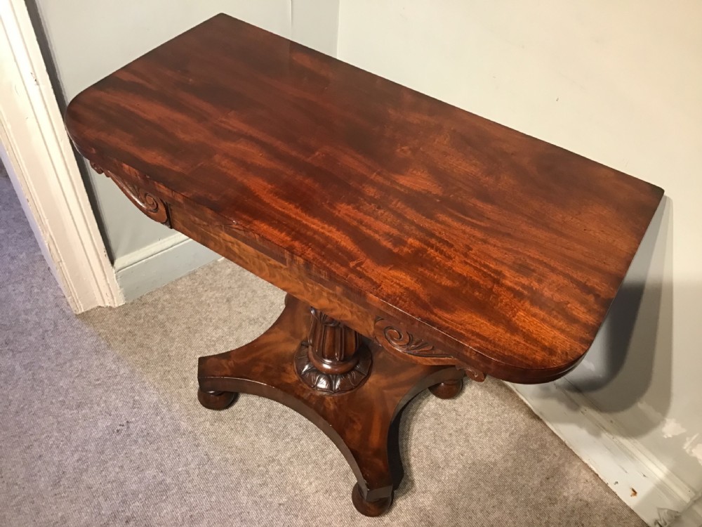 A Regency period flame mahogany fold-over card table featuring a carved pedestal column, a quadruped platform base, and scroll corner brackets. View III