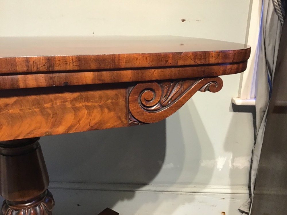 A Regency period flame mahogany fold-over card table featuring a carved pedestal column, a quadruped platform base, and scroll corner brackets. View VII