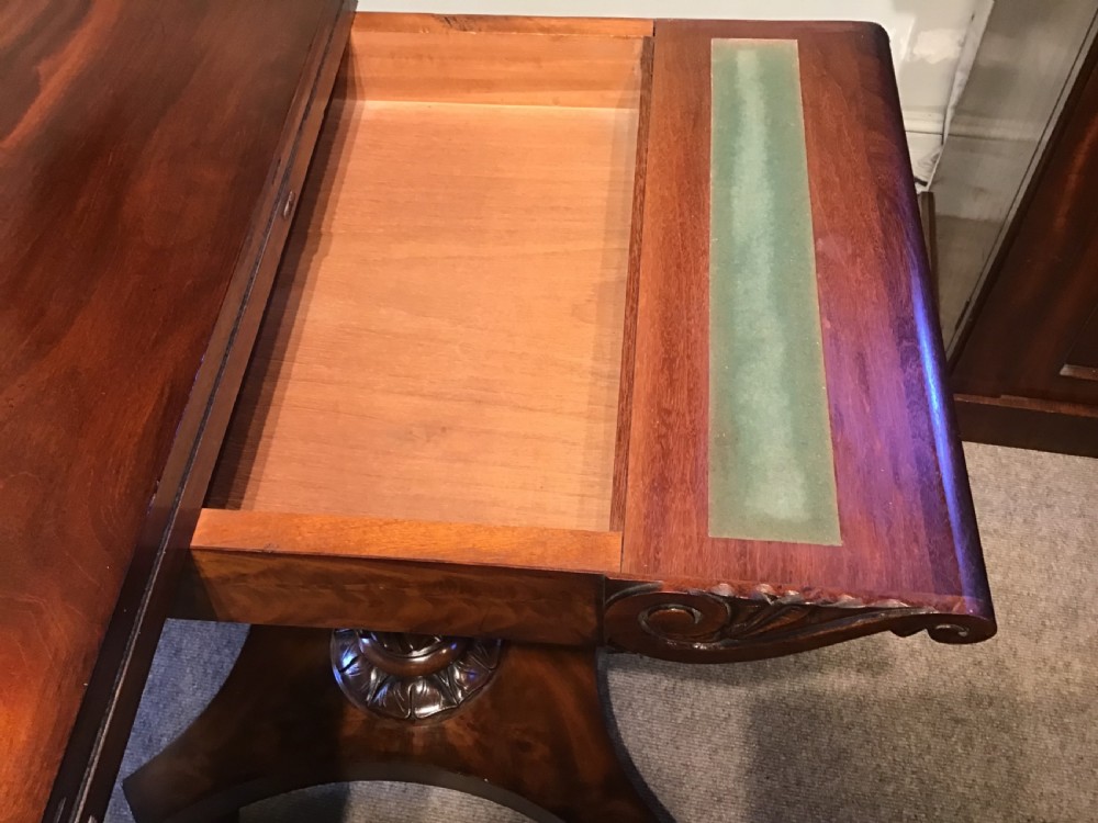 A Regency period flame mahogany fold-over card table featuring a carved pedestal column, a quadruped platform base, and scroll corner brackets. View XVII
