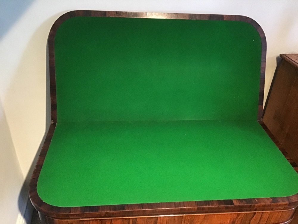 A Regency rosewood card table featuring a rectangular swivel top with rounded corners, supported by a central pedestal column and splayed legs ending in brass lions paw castors. View IX