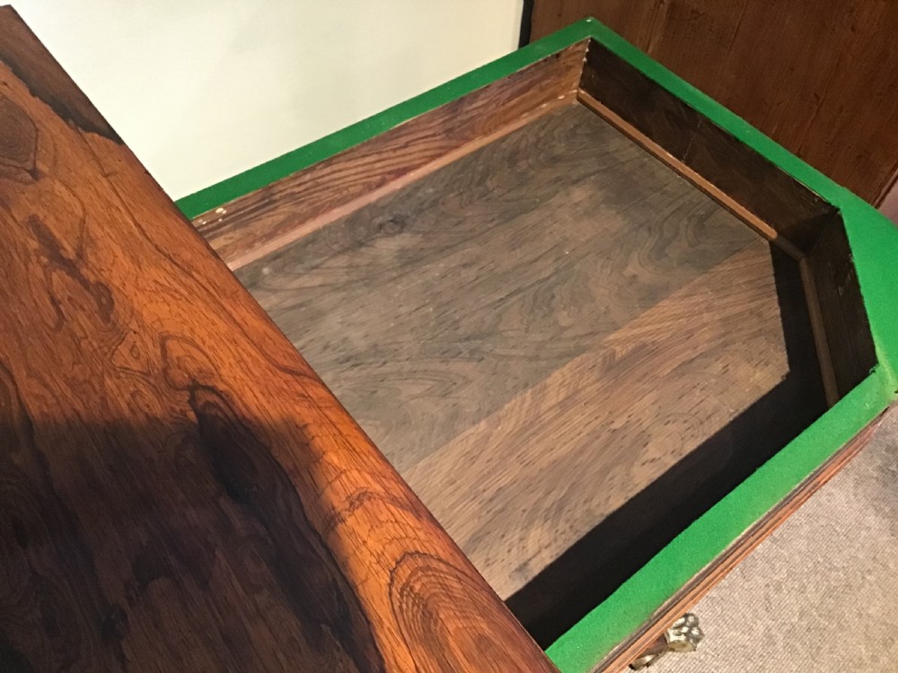 A Regency rosewood card table featuring a rectangular swivel top with rounded corners, supported by a central pedestal column and splayed legs ending in brass lions paw castors. View X