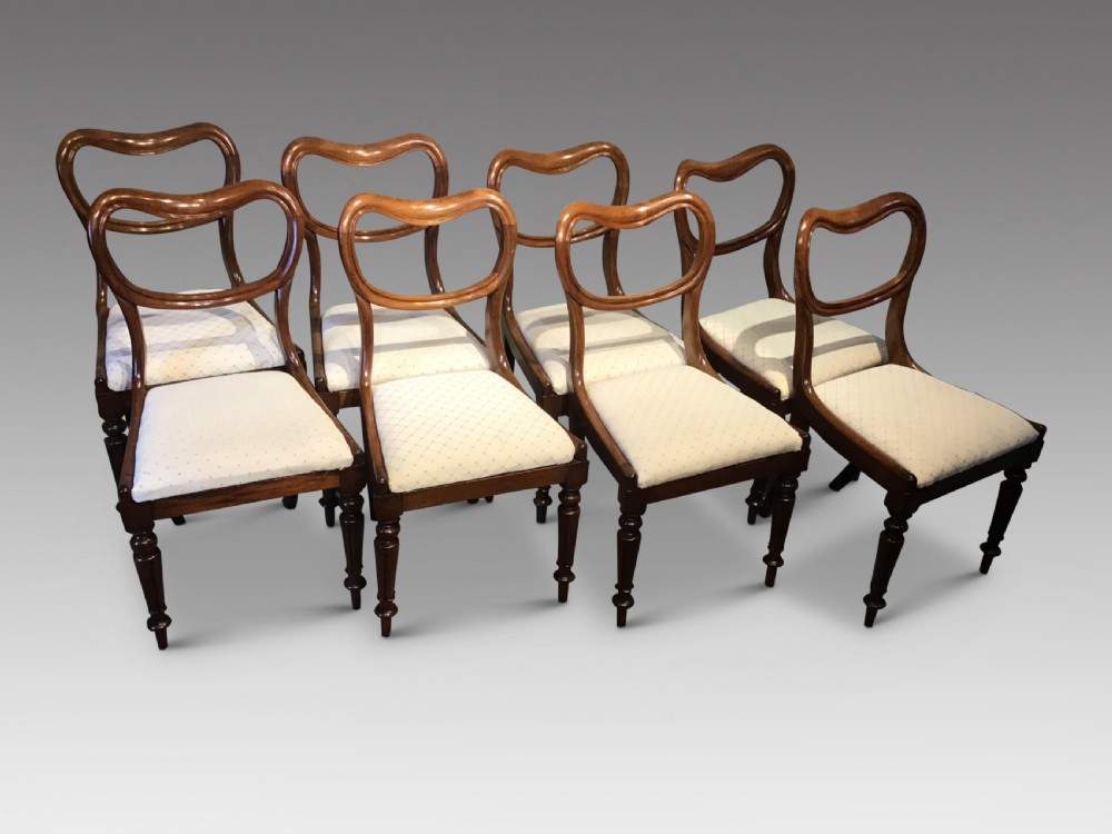 A set of eight Victorian mahogany balloon back dining chairs featuring turned front legs and light cream patterned upholstered seats. View II