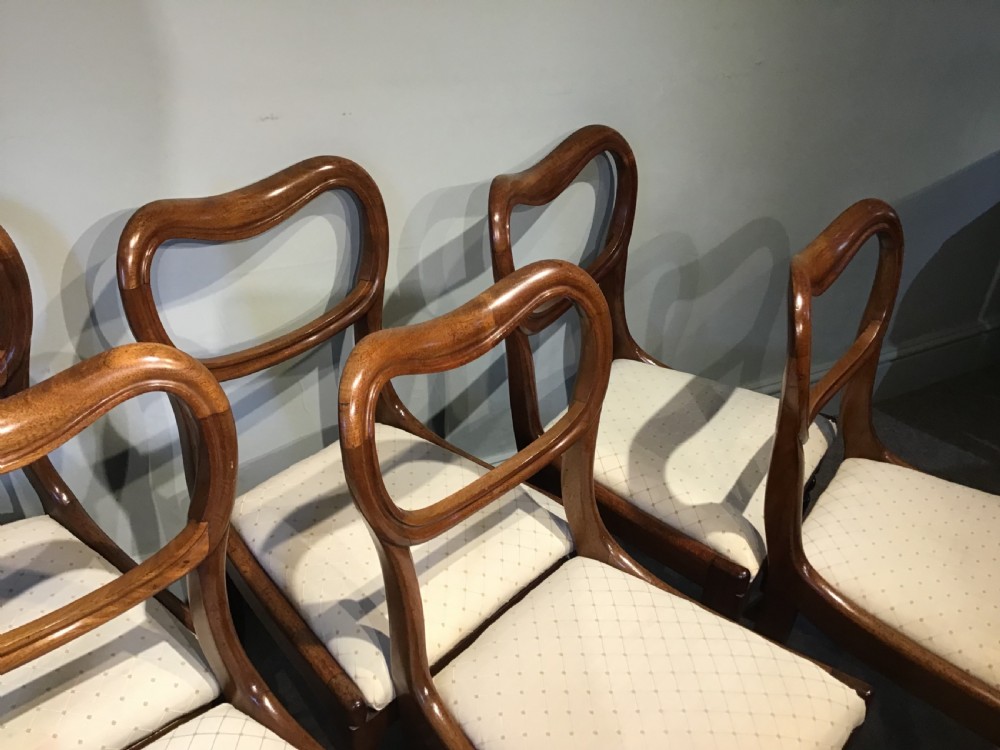 A set of eight Victorian mahogany balloon back dining chairs featuring turned front legs and light cream patterned upholstered seats. View IV