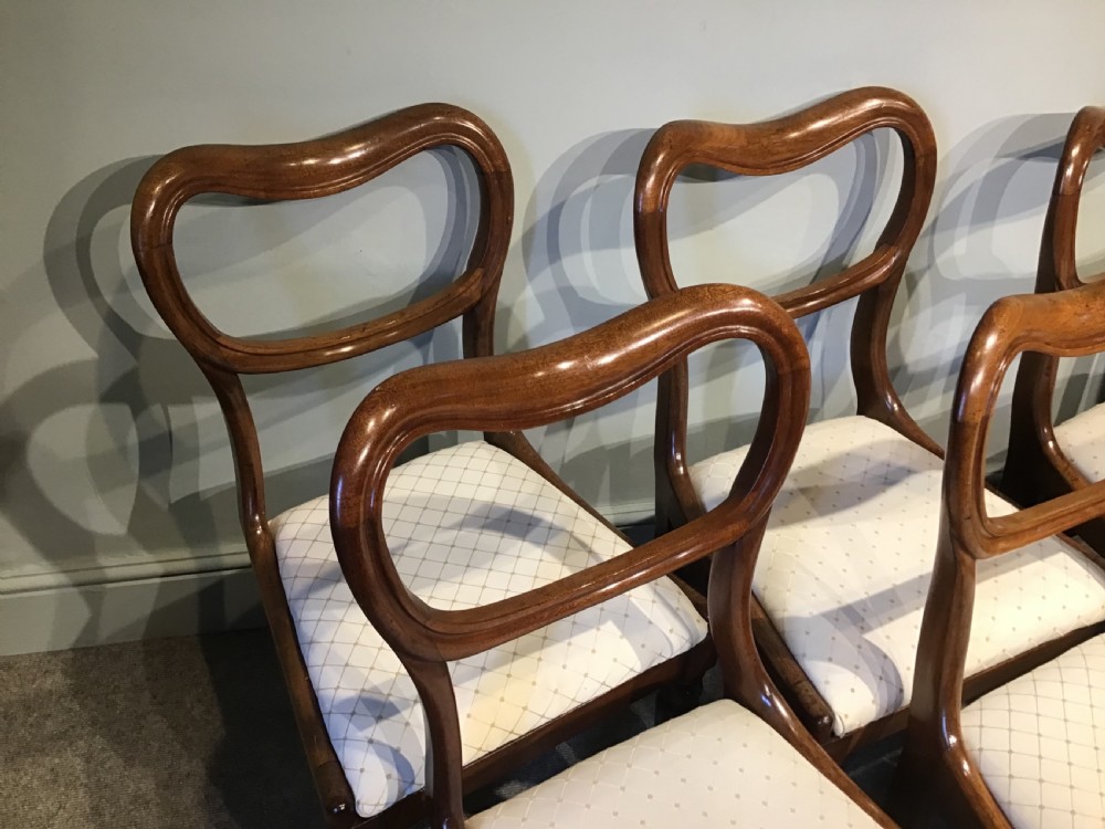 A set of eight Victorian mahogany balloon back dining chairs featuring turned front legs and light cream patterned upholstered seats. View V