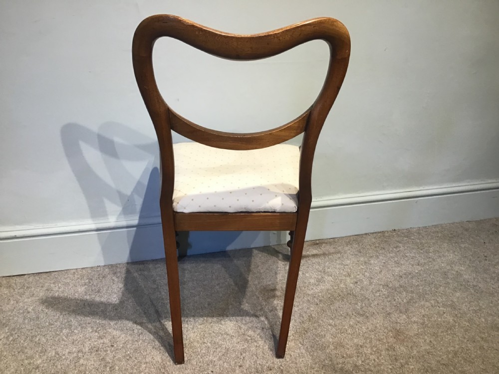 A set of eight Victorian mahogany balloon back dining chairs featuring turned front legs and light cream patterned upholstered seats. View IX