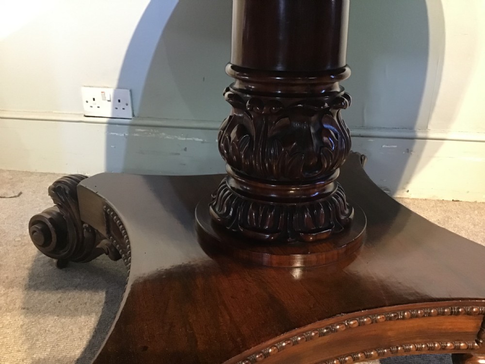 A circular antique Goncalo Alves centre table featuring a figured timber top and a pedestal base with carved scroll feet. View IV