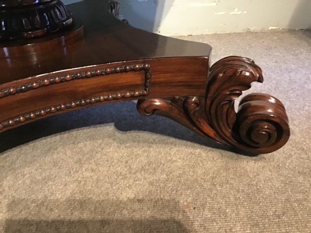 A circular antique Goncalo Alves centre table featuring a figured timber top and a pedestal base with carved scroll feet. View VI