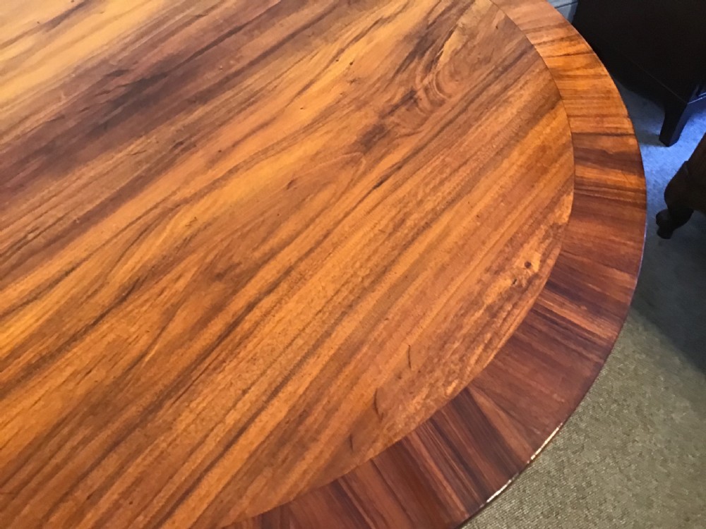 A circular antique Goncalo Alves centre table featuring a figured timber top and a pedestal base with carved scroll feet. View VII