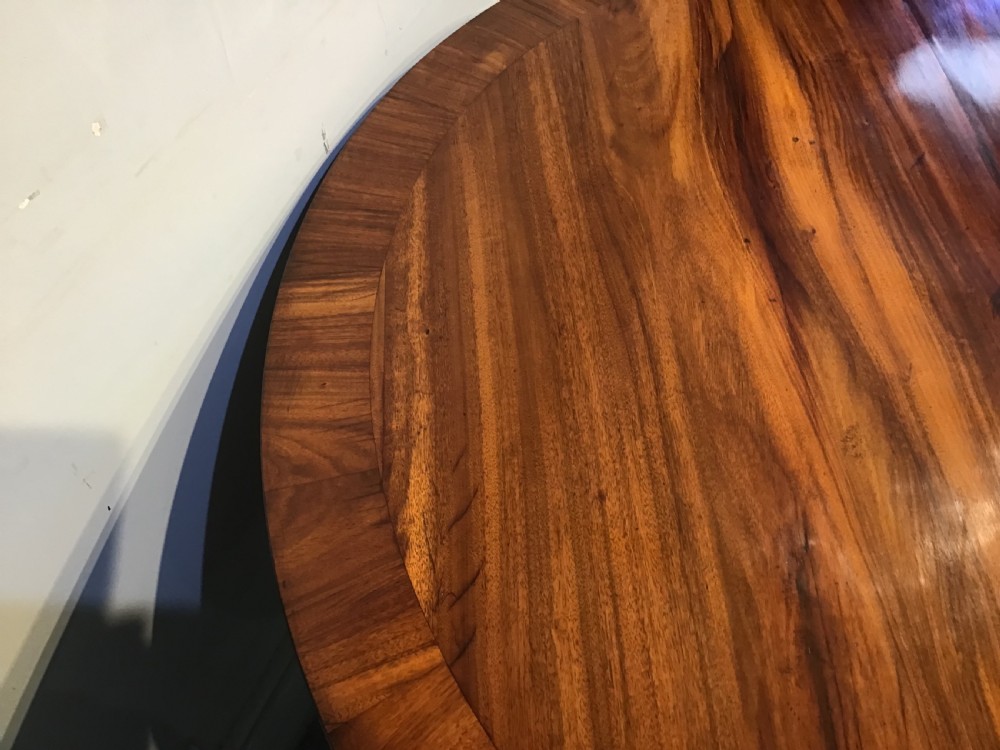 A circular antique Goncalo Alves centre table featuring a figured timber top and a pedestal base with carved scroll feet. View IX