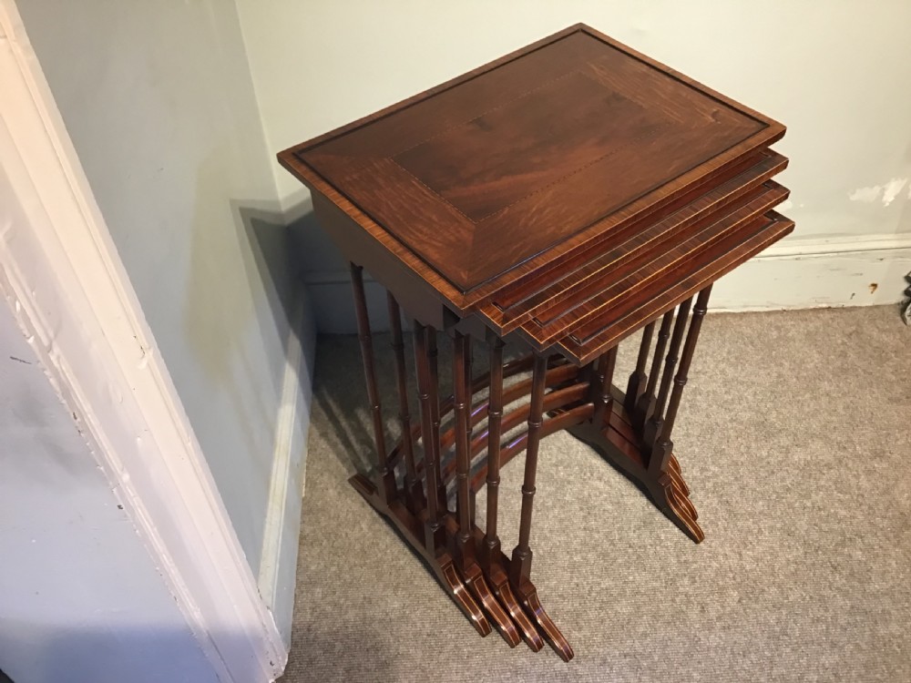 A set of four graduated dark mahogany nested tables featuring turned legs, curved rear stretchers, and splayed feet. View III