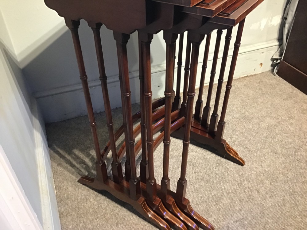 A set of four graduated dark mahogany nested tables featuring turned legs, curved rear stretchers, and splayed feet. View V