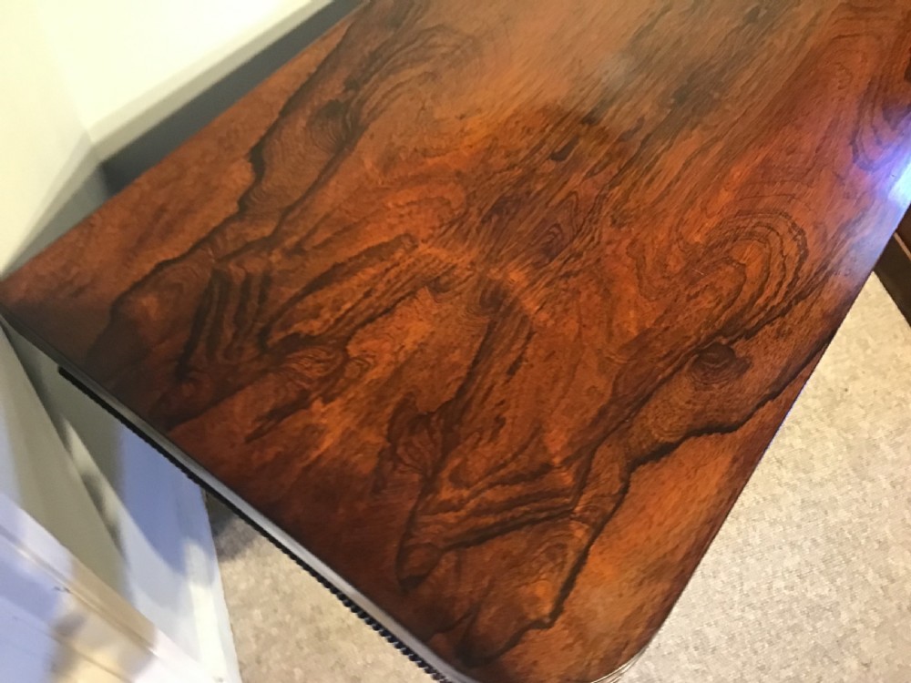 An antique rosewood fold-over card table with a beaded frieze, central turned pedestal stem, and a quadripartite plinth base on carved feet. View VII
