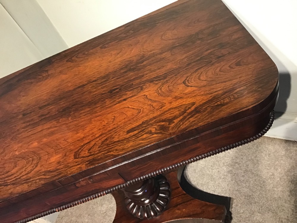 An antique rosewood fold-over card table with a beaded frieze, central turned pedestal stem, and a quadripartite plinth base on carved feet. View VIII