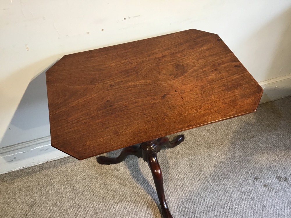 A dark mahogany Georgian tripod table with a canted rectangular top, central turned column, and three cabriole legs. View III
