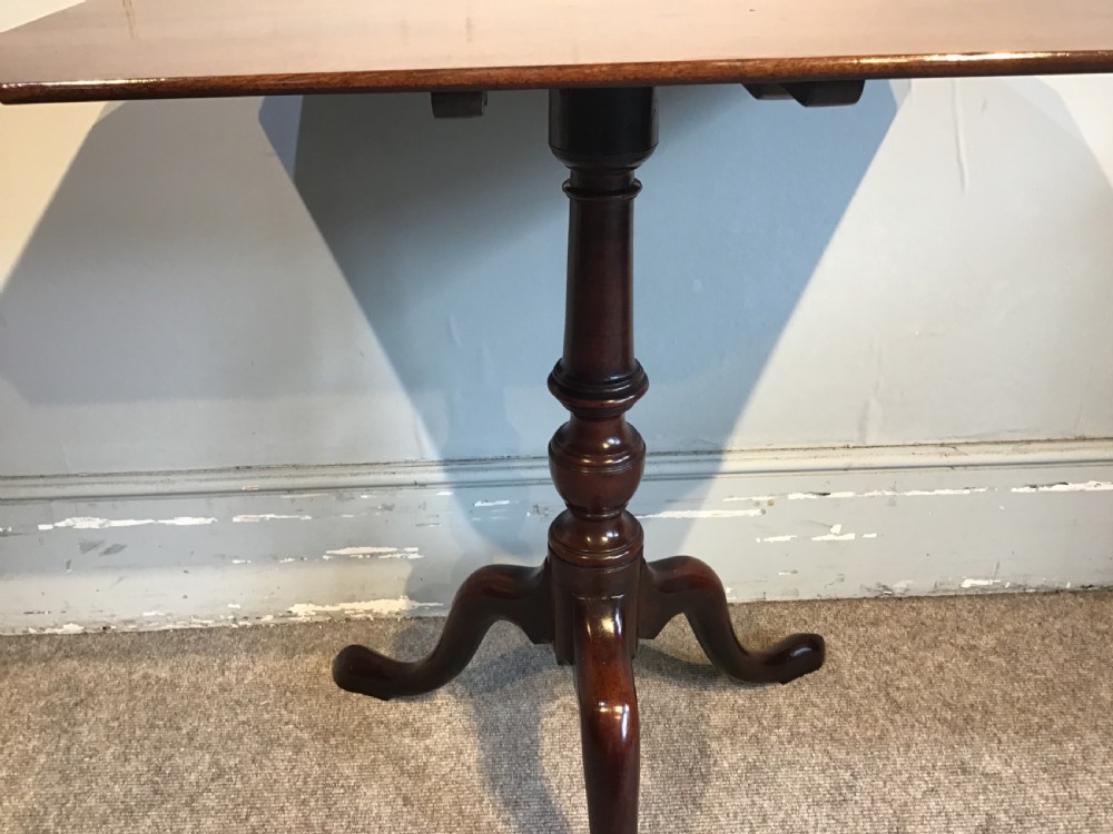 A dark mahogany Georgian tripod table with a canted rectangular top, central turned column, and three cabriole legs. View VI