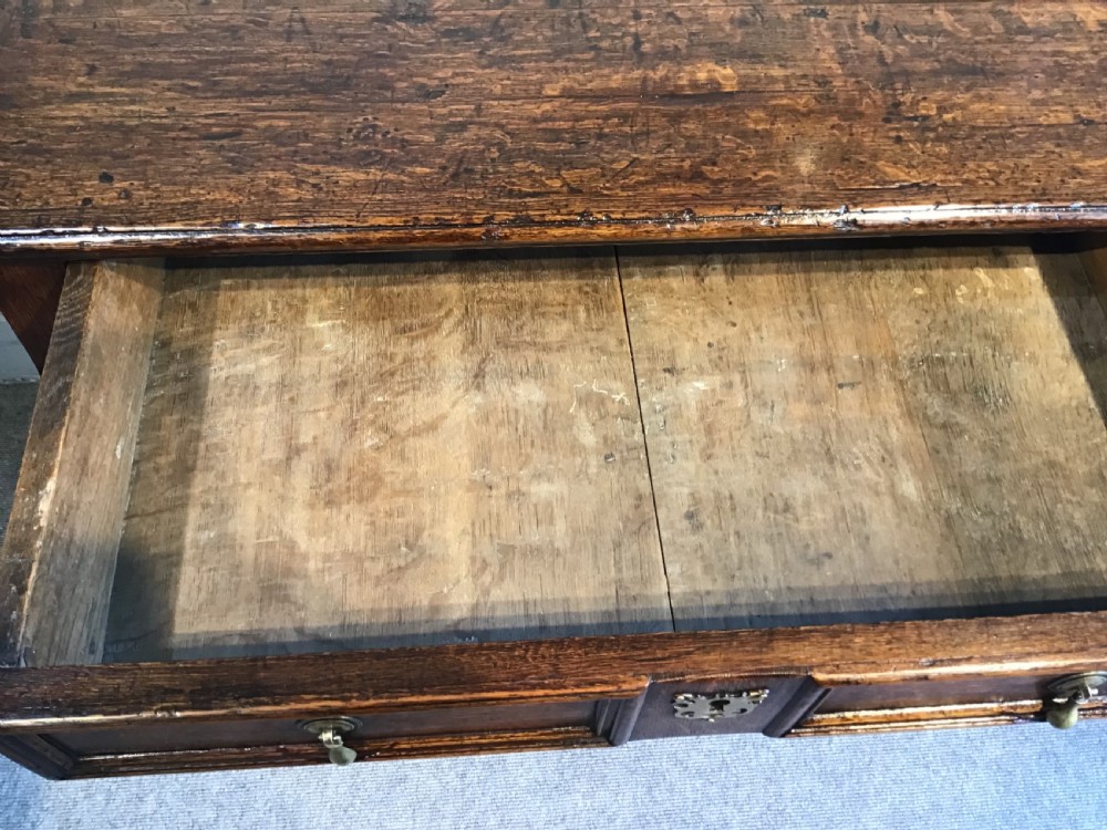An antique dark brown oak chest featuring four drawers with geometric panel mouldings, brass teardrop handles, escutcheons, and bun feet. View IX