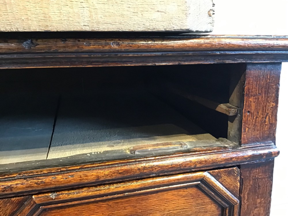 An antique dark brown oak chest featuring four drawers with geometric panel mouldings, brass teardrop handles, escutcheons, and bun feet. View XI