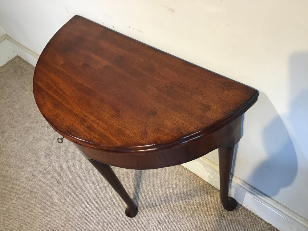 A Georgian mahogany semi-circular fold-over tea table featuring slender legs terminating in pad feet and a brass keyhole escutcheon. View IV