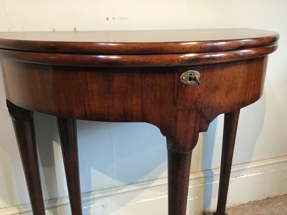 A Georgian mahogany semi-circular fold-over tea table featuring slender legs terminating in pad feet and a brass keyhole escutcheon. View VIII