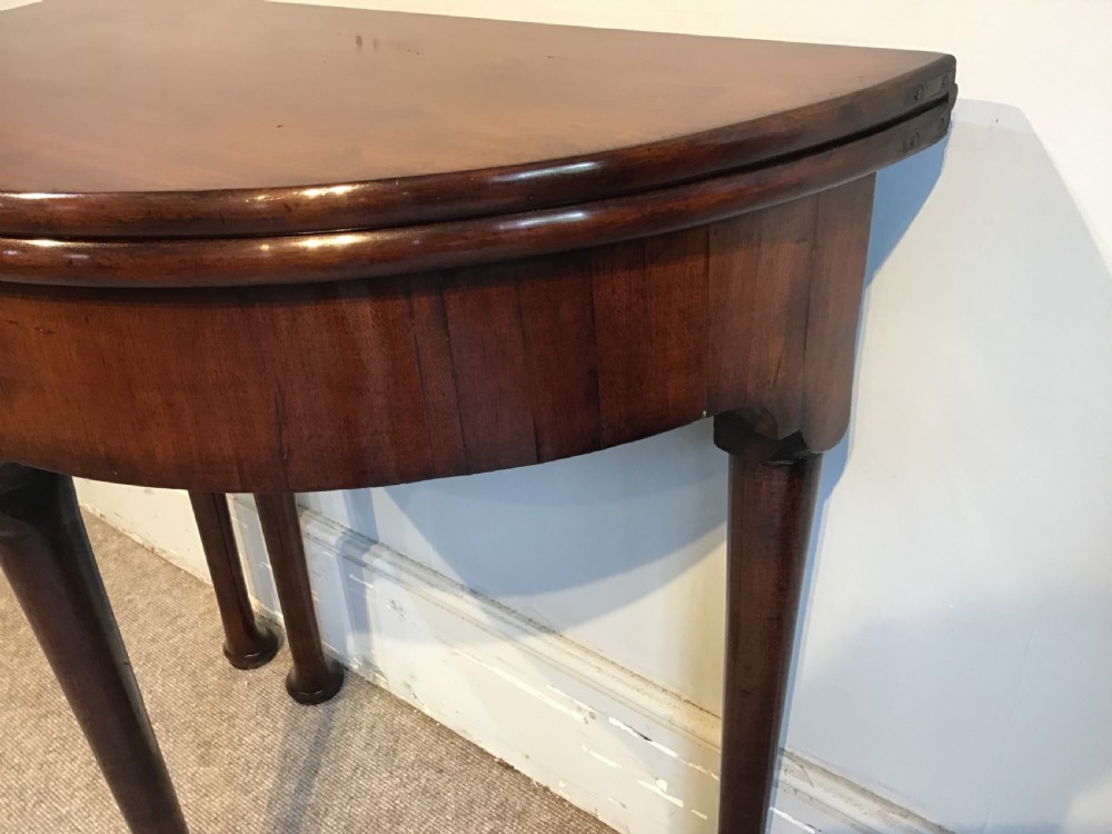 A Georgian mahogany semi-circular fold-over tea table featuring slender legs terminating in pad feet and a brass keyhole escutcheon. View X