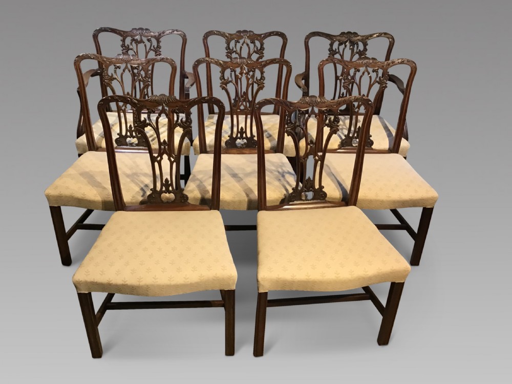 A set of eight Georgian mahogany dining chairs featuring intricate carved pierced back splats and cream patterned upholstered seats.