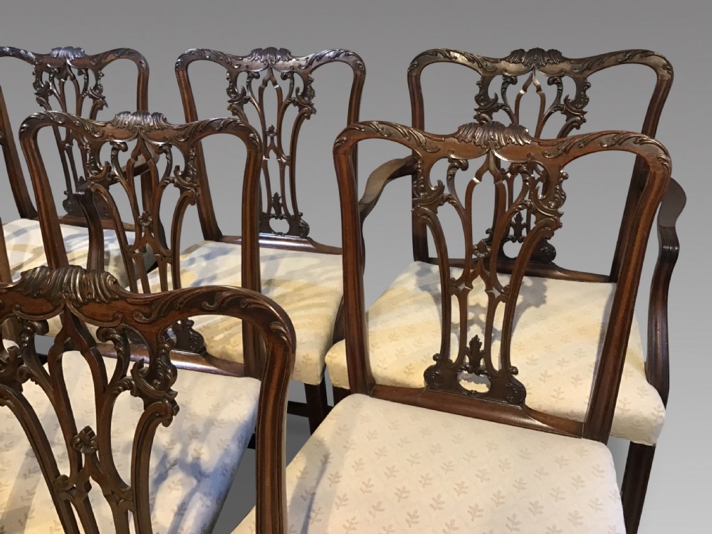 A set of eight Georgian mahogany dining chairs featuring intricate carved pierced back splats and cream patterned upholstered seats. View II