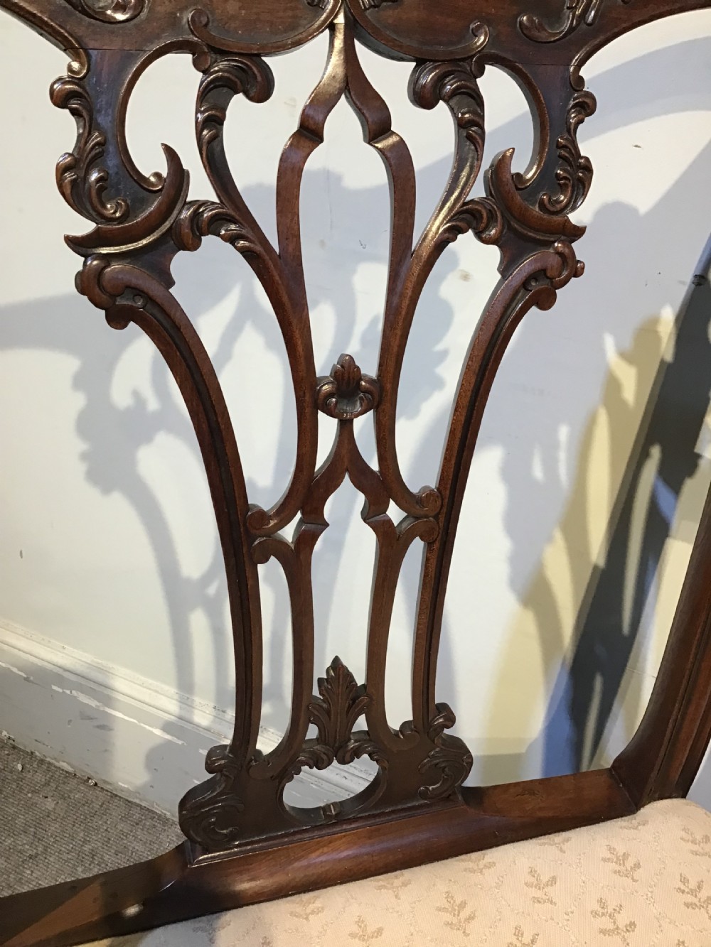 A set of eight Georgian mahogany dining chairs featuring intricate carved pierced back splats and cream patterned upholstered seats. View VI