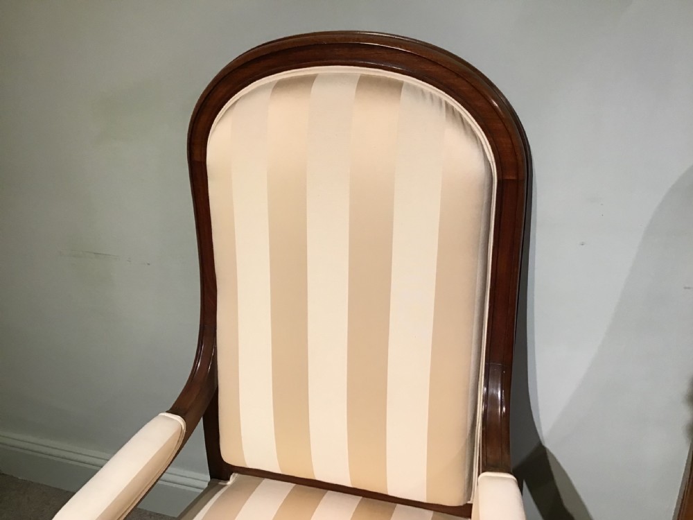 A pair of antique mahogany armchairs featuring tall arched backs, cream striped upholstery, scrolled armrests, and turned legs on castors. View II