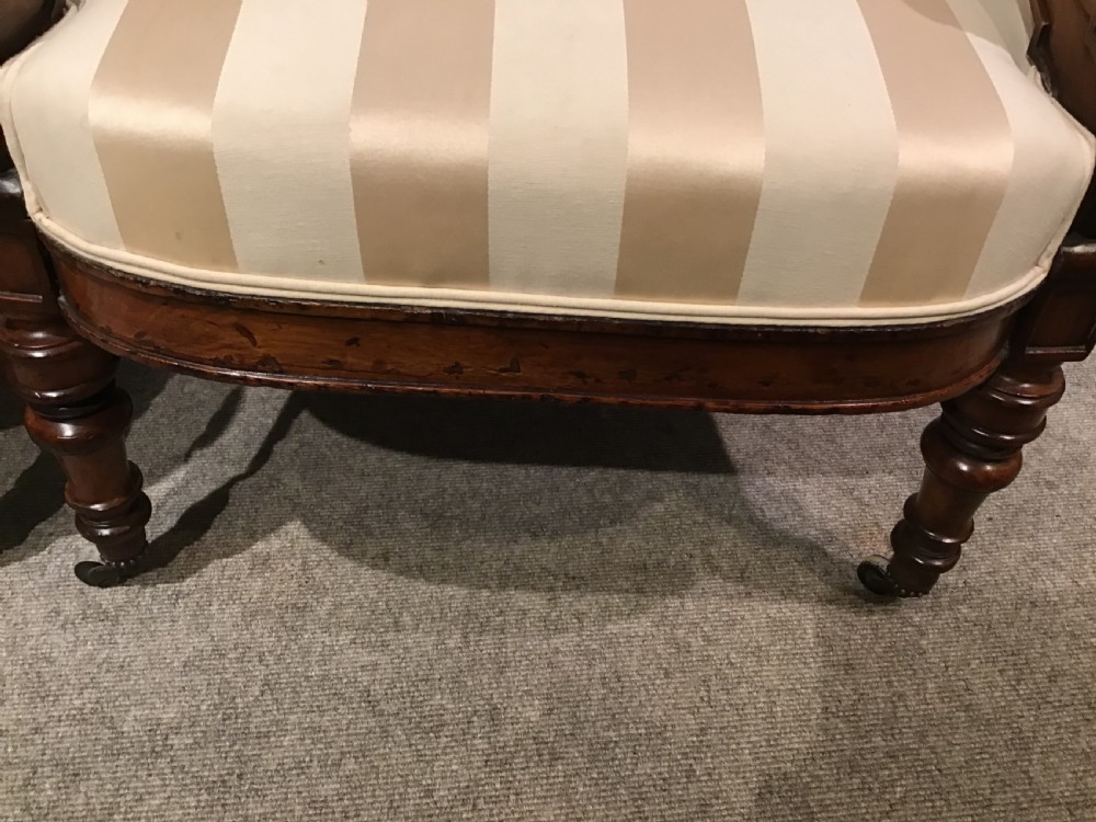 A pair of antique mahogany armchairs featuring tall arched backs, cream striped upholstery, scrolled armrests, and turned legs on castors. View IV
