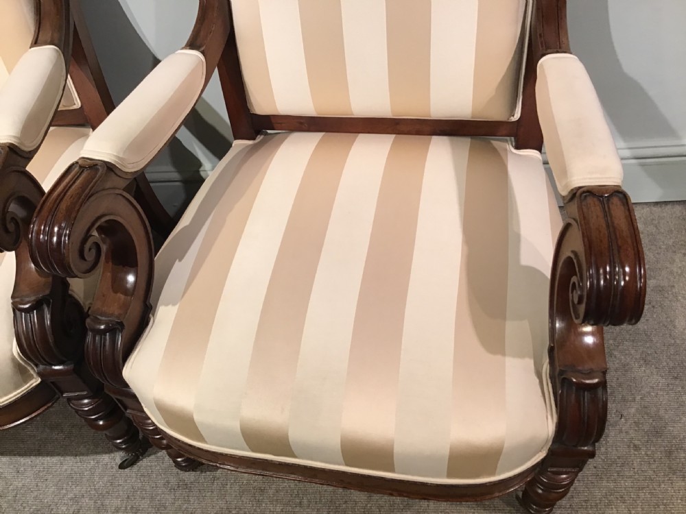 A pair of antique mahogany armchairs featuring tall arched backs, cream striped upholstery, scrolled armrests, and turned legs on castors. View VI
