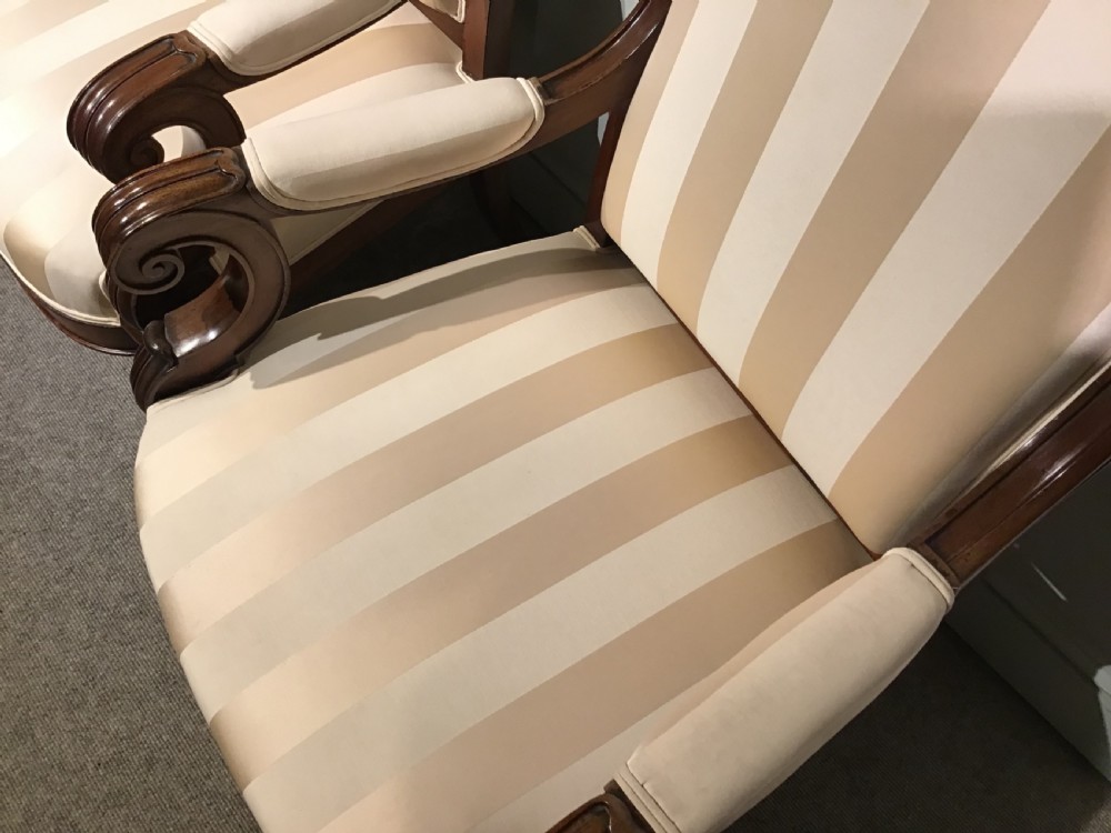 A pair of antique mahogany armchairs featuring tall arched backs, cream striped upholstery, scrolled armrests, and turned legs on castors. View VIII