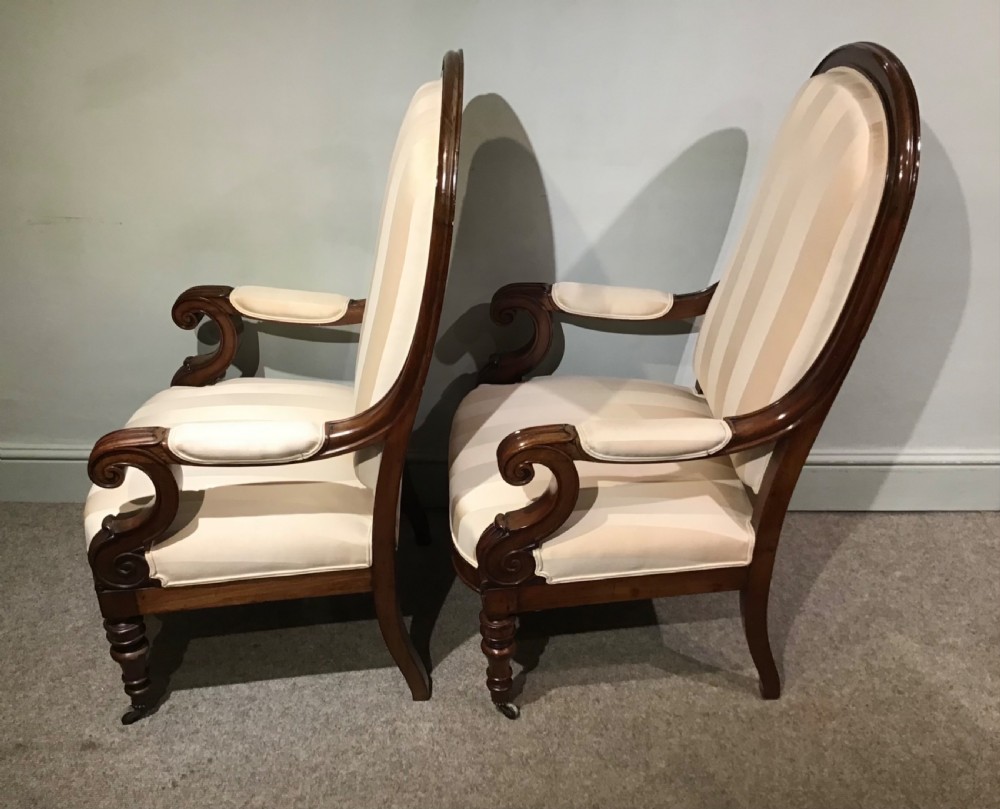 A pair of antique mahogany armchairs featuring tall arched backs, cream striped upholstery, scrolled armrests, and turned legs on castors. View IX