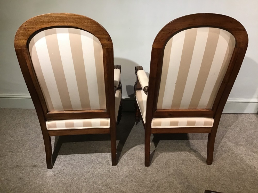 A pair of antique mahogany armchairs featuring tall arched backs, cream striped upholstery, scrolled armrests, and turned legs on castors. View XI