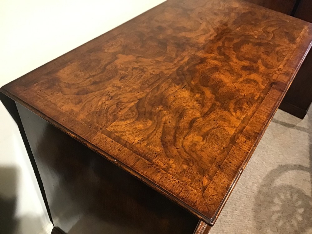 An antique burr walnut chest of drawers with two short over three long drawers, brass handles, and bun feet. View V