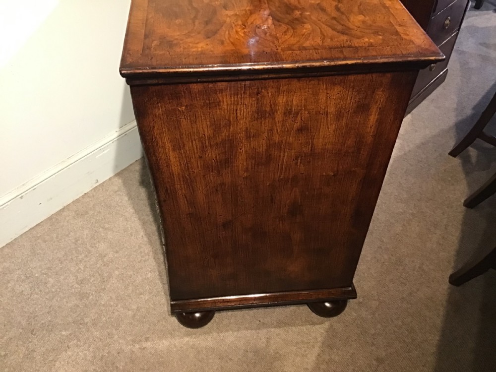 An antique burr walnut chest of drawers with two short over three long drawers, brass handles, and bun feet. View X