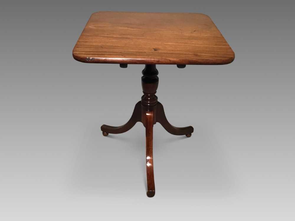 A Georgian mahogany tripod table featuring a square top with rounded corners, supported by a turned central pedestal and three splayed legs.